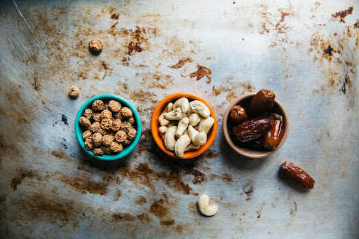 Healthy snacks supporting sustained energy during the workday Small bowls of mixed nuts and dates arranged on a table, representing nutritious snacks for energy, focus, and balanced workplace nutrition.