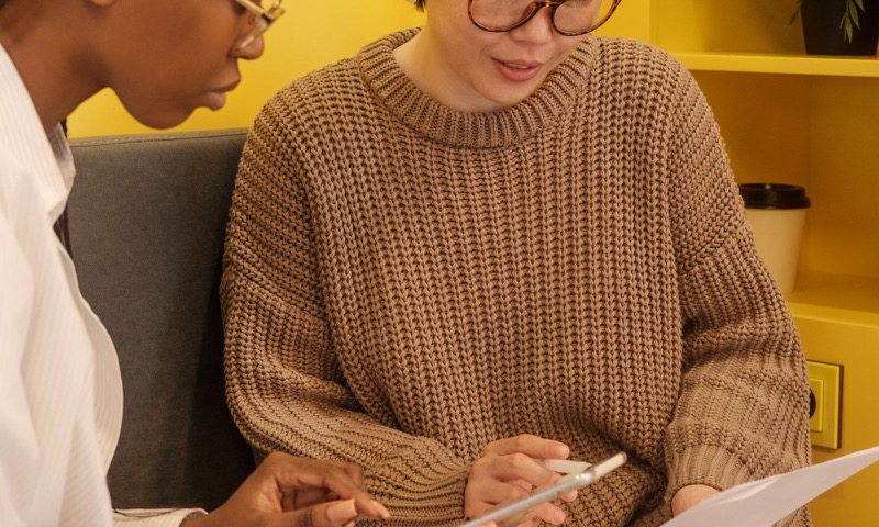 Two colleagues reviewing documents and a tablet in a workplace meeting