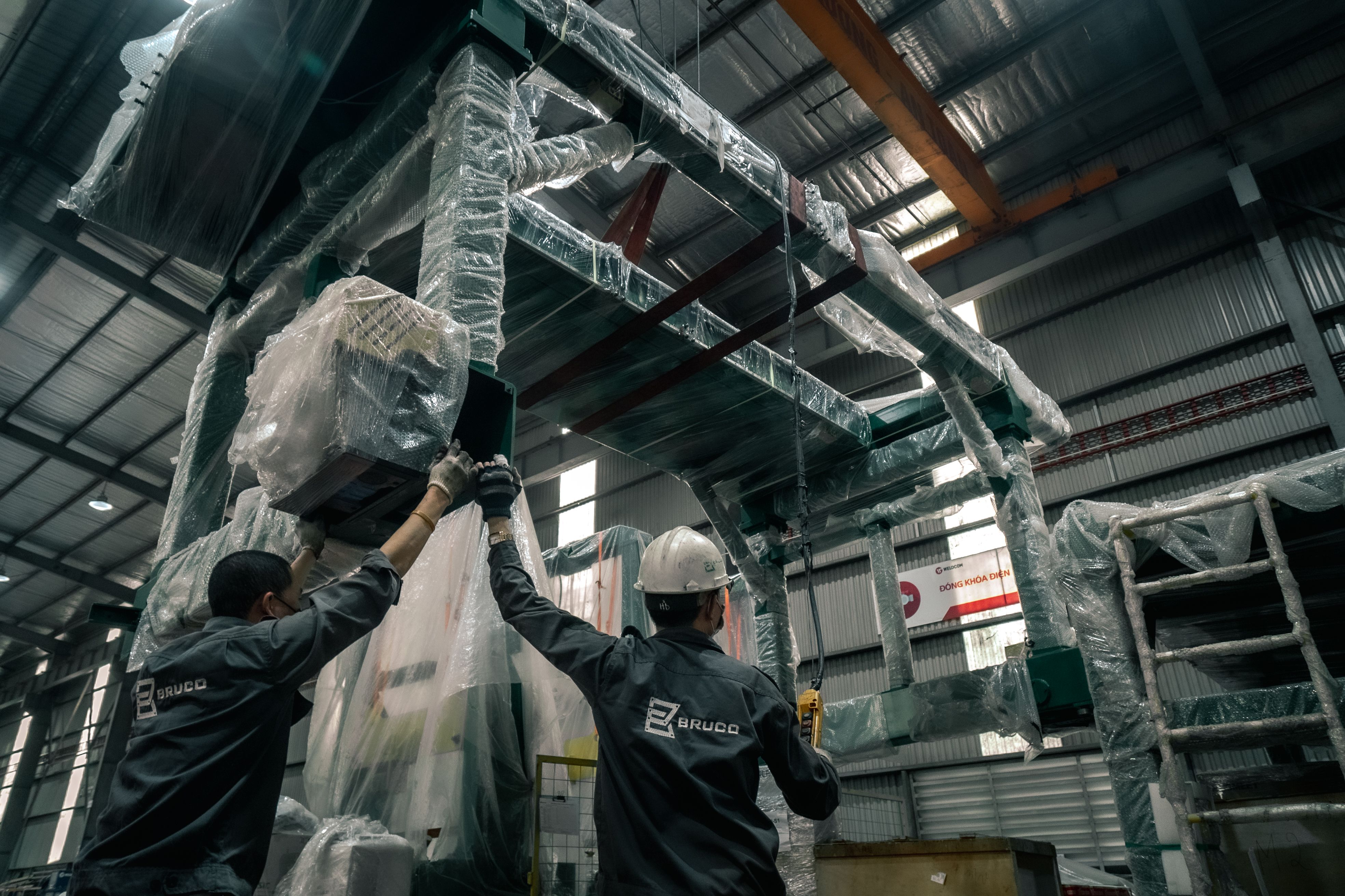 Workers installing machinery in an industrial warehouse.