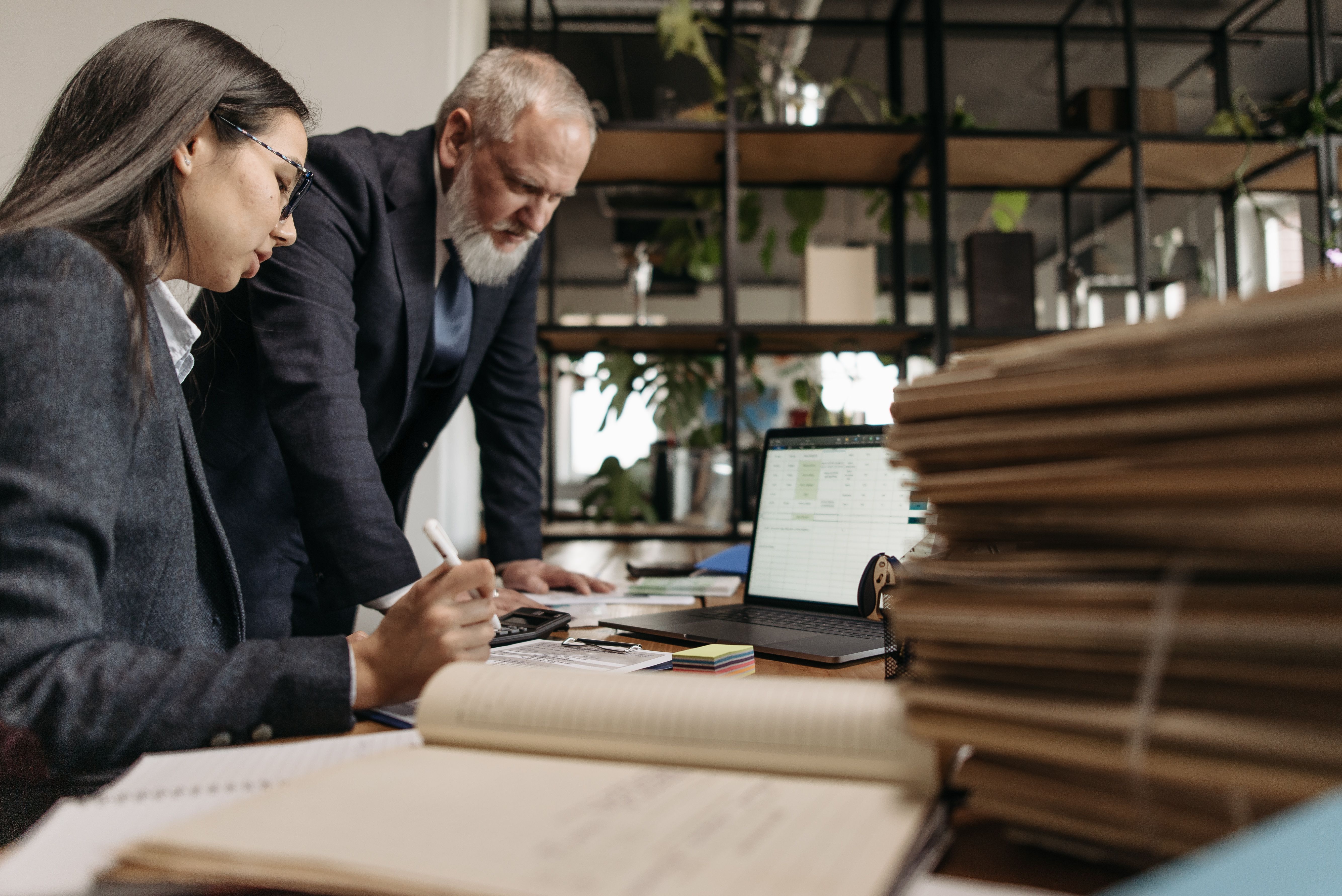 Two colleagues review documents together at an office desk