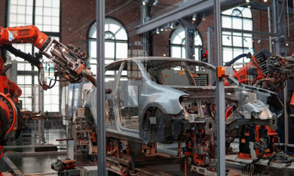 Industrial robots assembling a car body on an automotive manufacturing line, representing workplace safety, automation, and modern vehicle production.