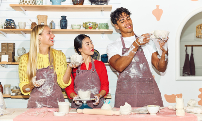 Three people making clay pots together in a pottery studio