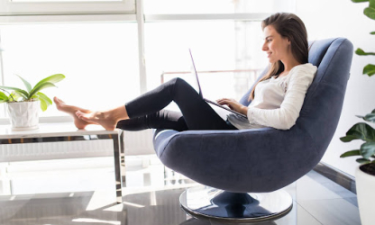 Person working on a laptop while sitting comfortably in a modern chair at home, representing remote work, everyday comfort, and balanced work-from-home routines.