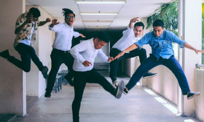 Group of colleagues jumping and laughing together in a hallway, representing workplace energy, team bonding, and playful company culture