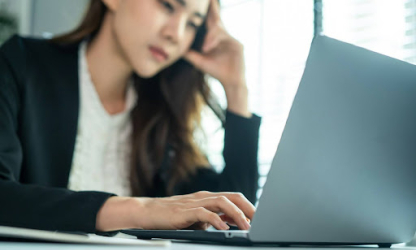 Professional woman concentrating while working on a laptop at a desk, representing cognitive focus, mental effort, and modern knowledge-based work.