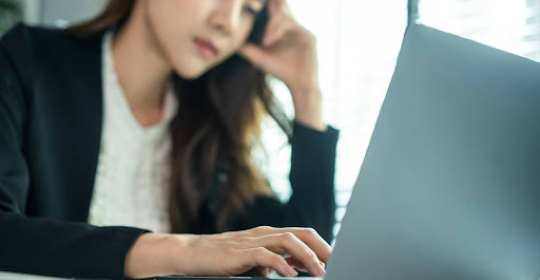 Professional woman concentrating while working on a laptop at a desk, representing cognitive focus, mental effort, and modern knowledge-based work.