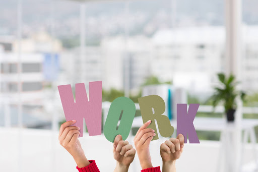 Positive work culture and teamwork in a modern office Employees holding colorful letters spelling “work,” symbolising teamwork and a positive workplace environment